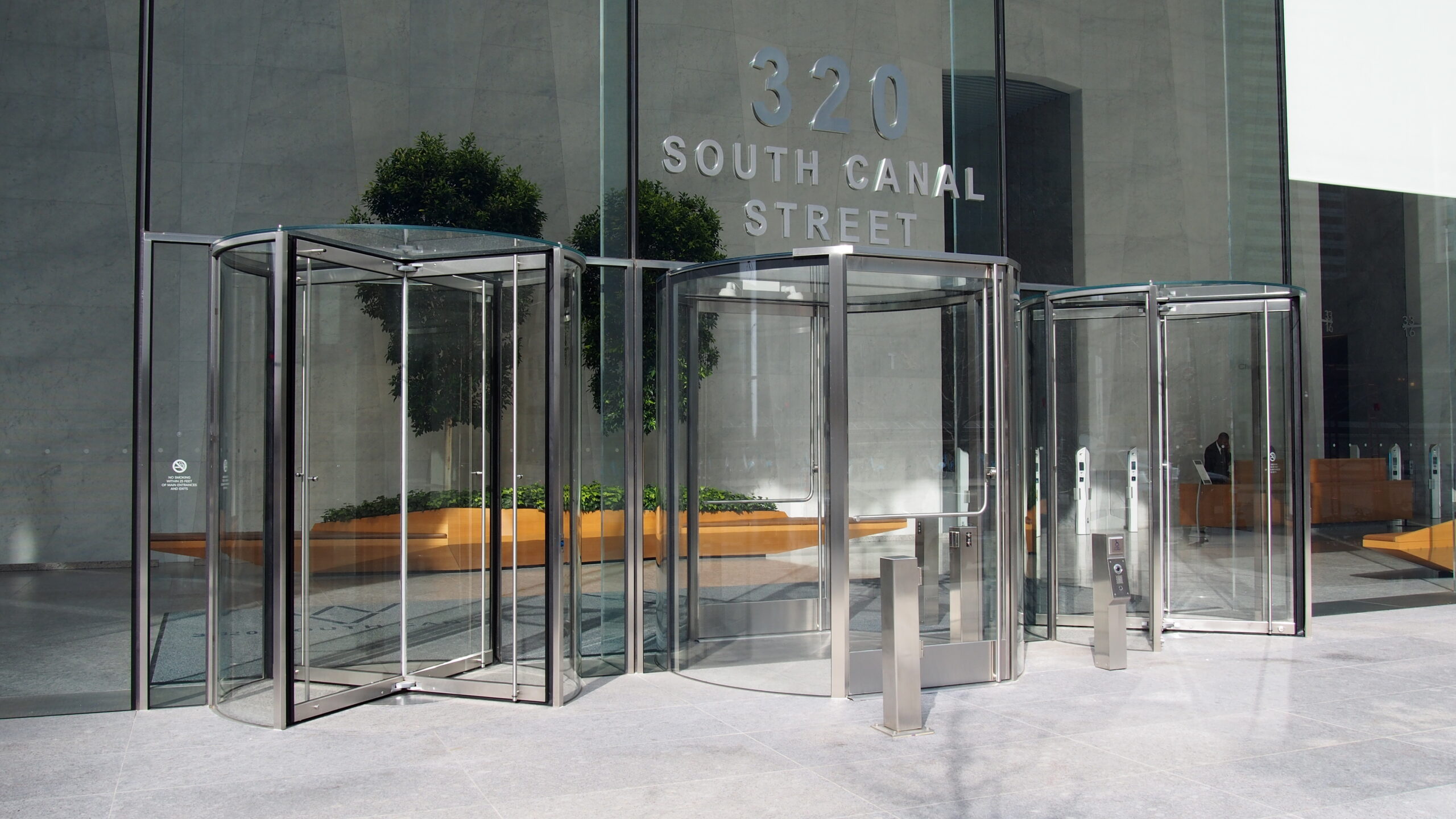 A photo of an architectural building product. An exterior entrance to the lobby of a large building, showing glass revolving doors.