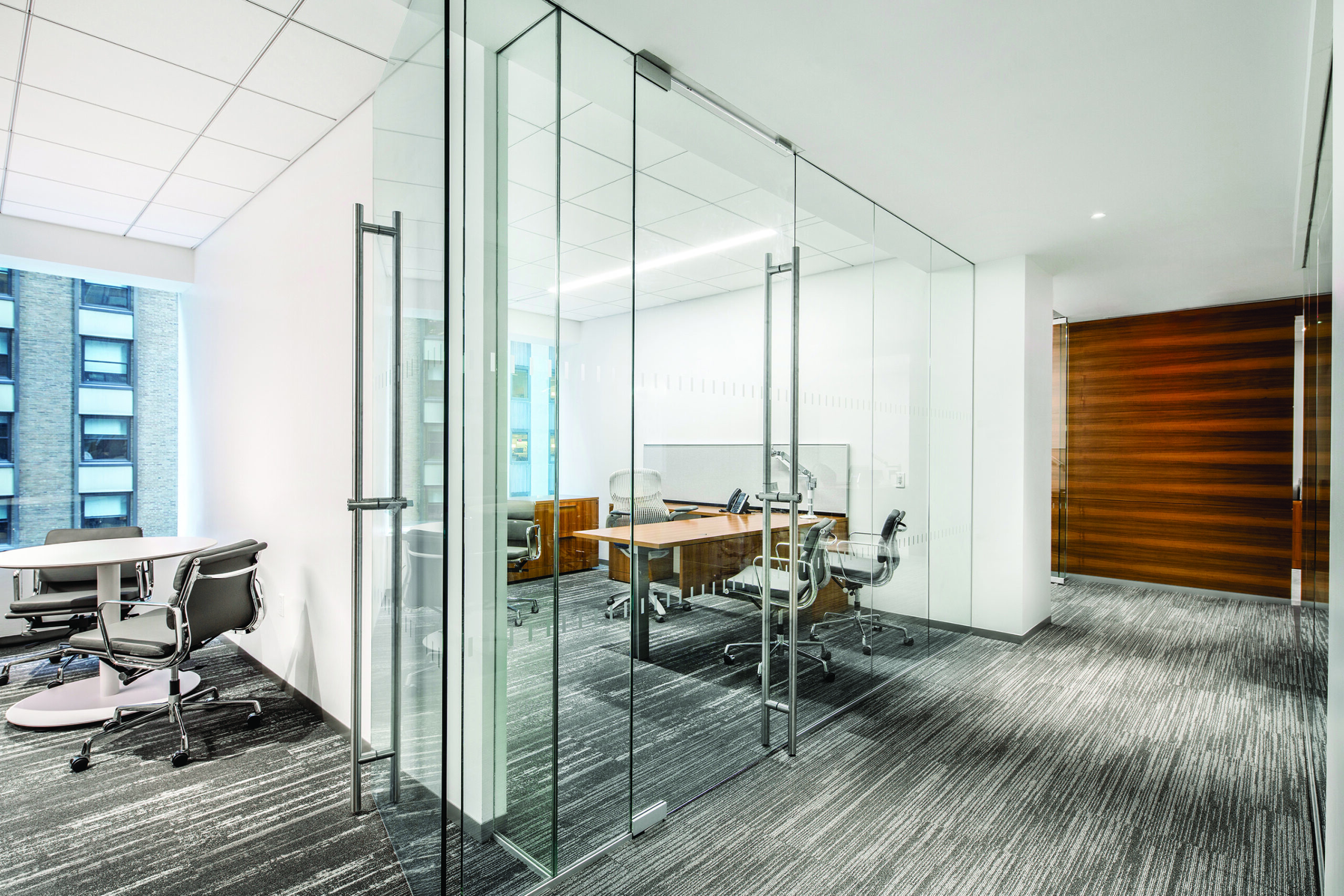 A photo of an architectural building product. An interior detail image, showing a glass wall and doors that open to an office room.